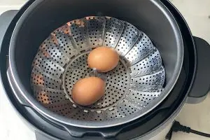 Ovos no cesto de cozimento a vapor da panela de pressão elétrica